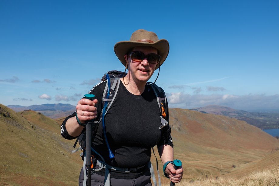 hiker with sun hat and poles on mountain