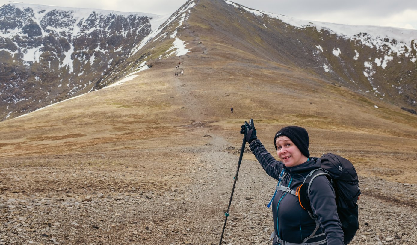 hiker pointing up towards lake distict peak