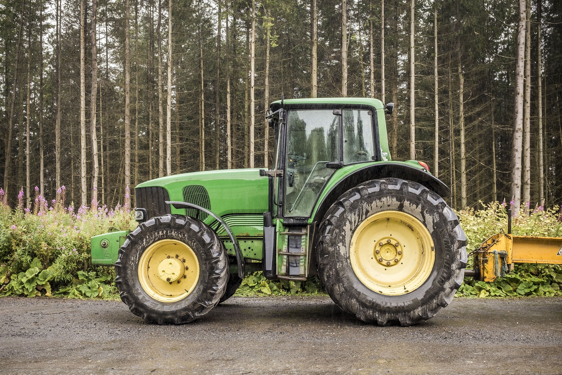green tractor in forest with large yellow wheels