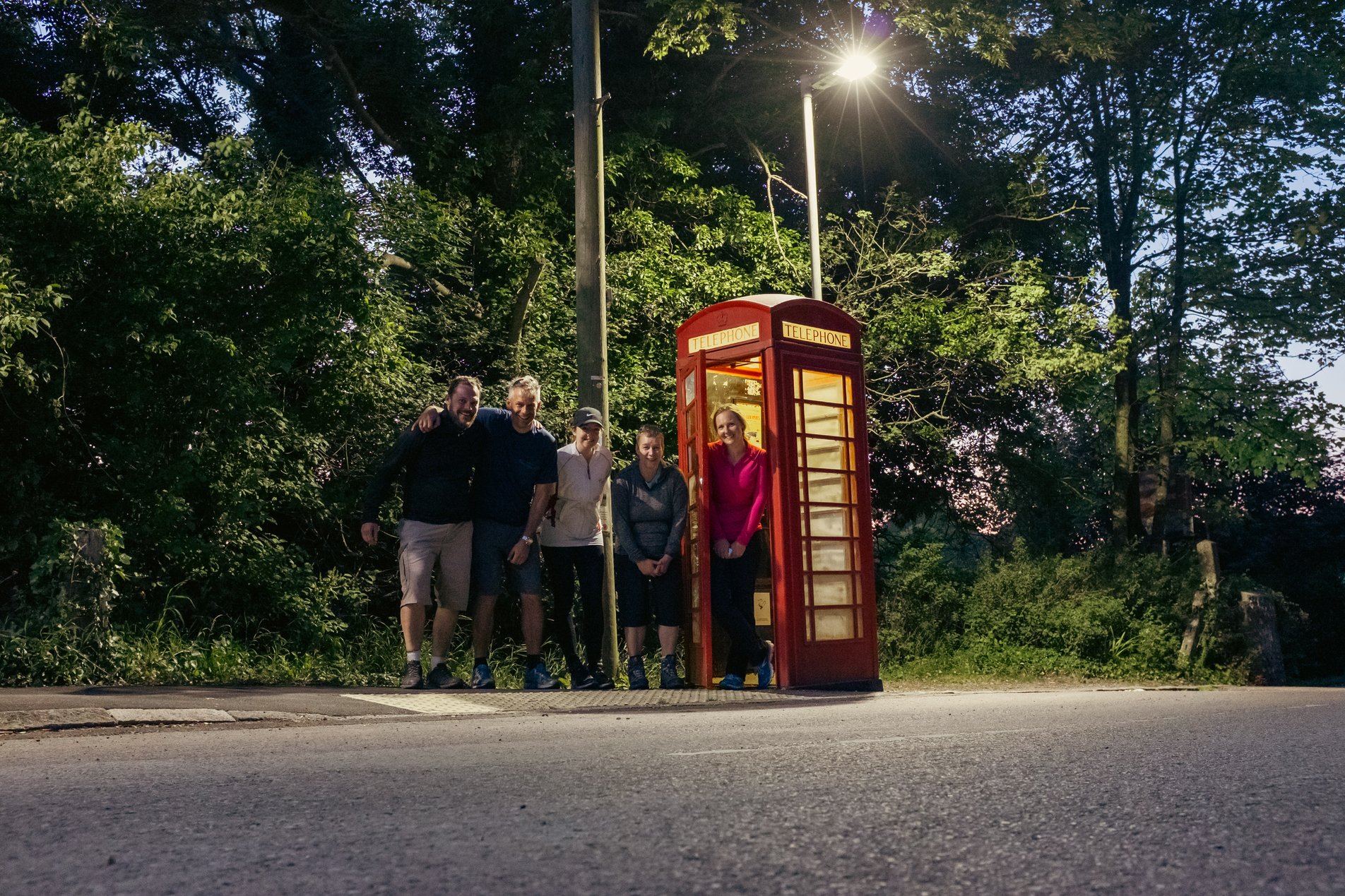 group shot of walkers around red telephone box at night
