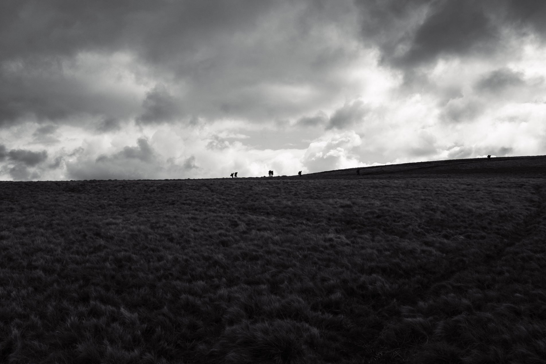 black and white mountain landscape with walkers on ridge