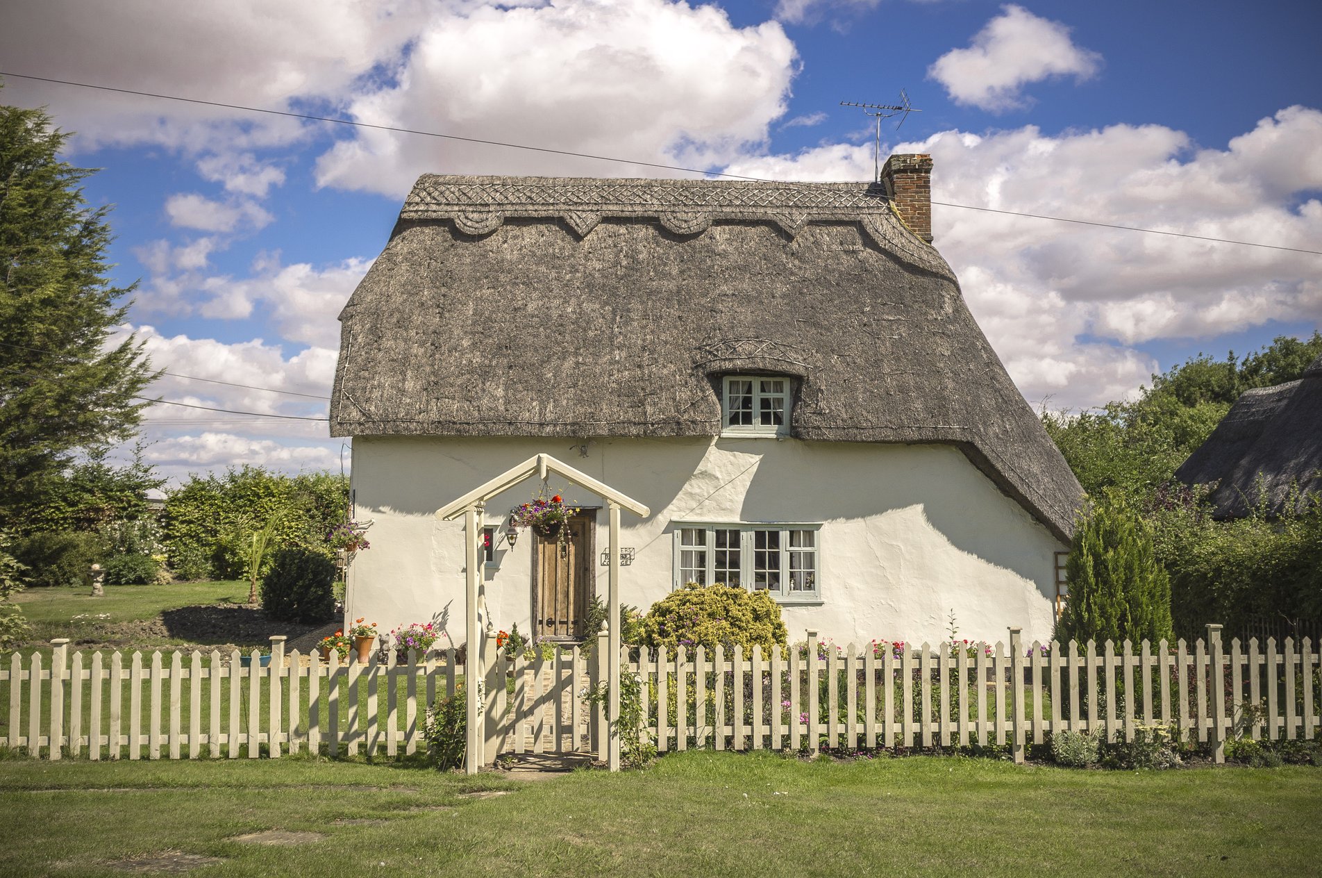 white thatched cottage with picket fence outside