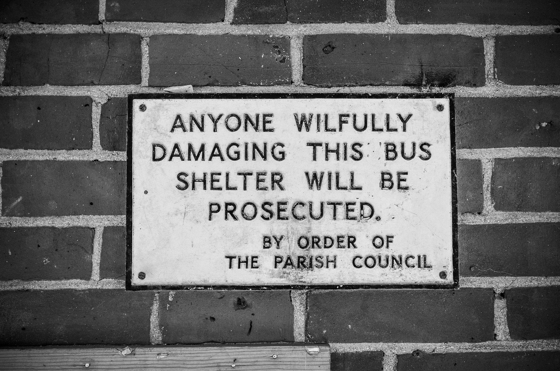 notice in bus shelter reading 'anyone wilfully damaging this bus shelter will be prosecuted. by order of the parish council.