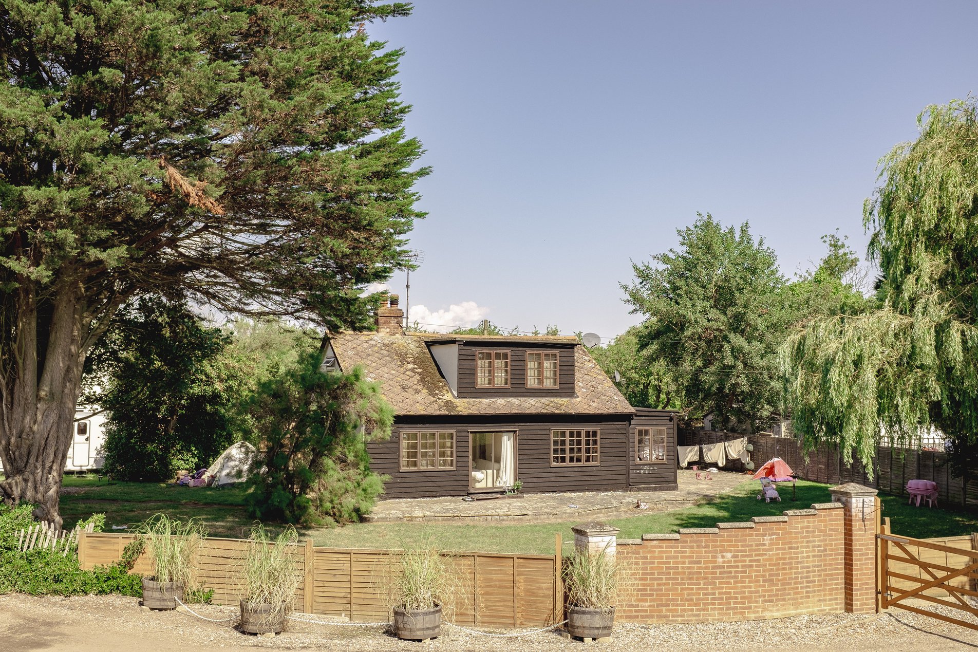 detached wood clad house behind fence and brick wall