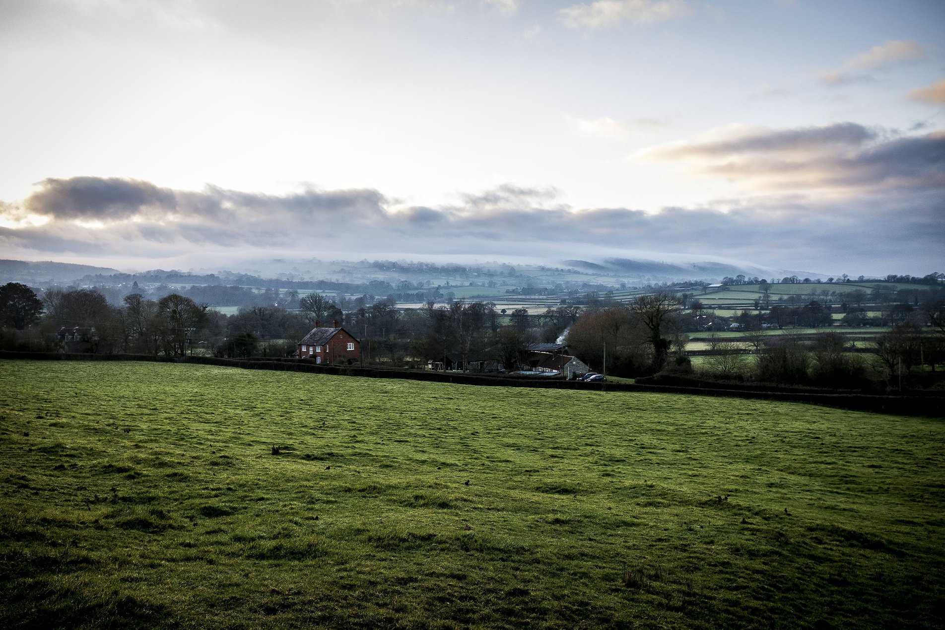 view across farmland with mist over distant hills