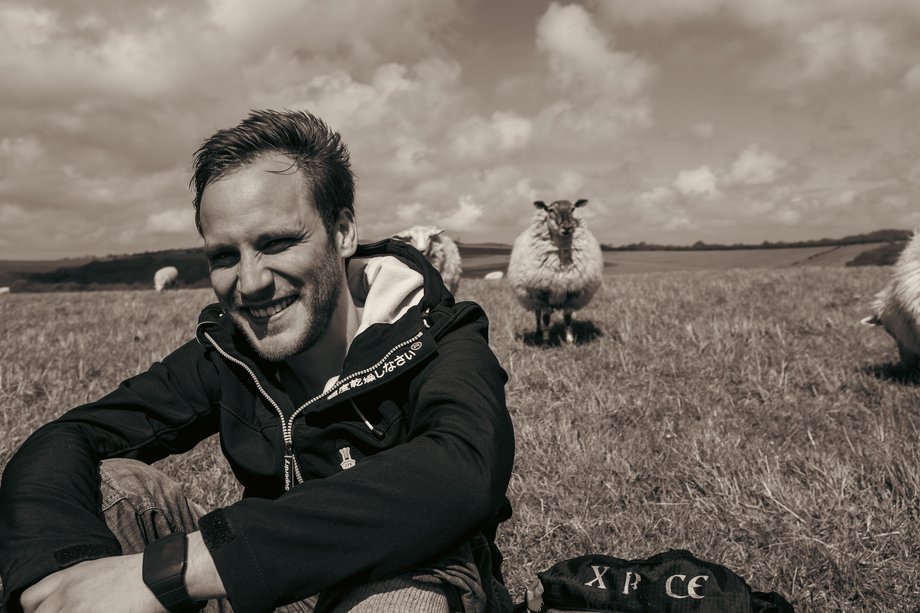 hiker sitting in field with sheep