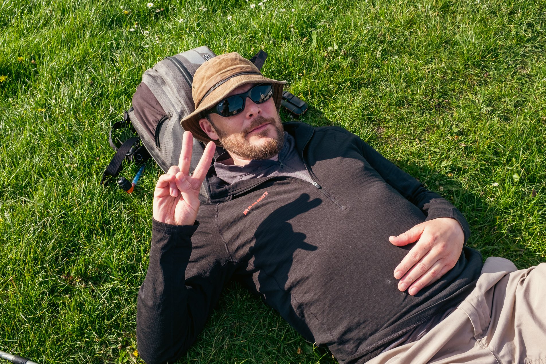 hiker lying on ground giving a peace sign to the camera