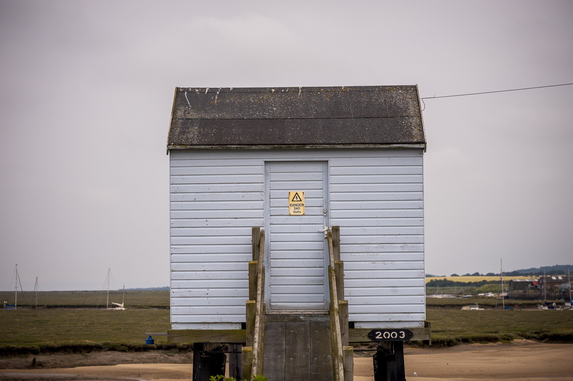 light blue wooden hut on stilts next to harbour