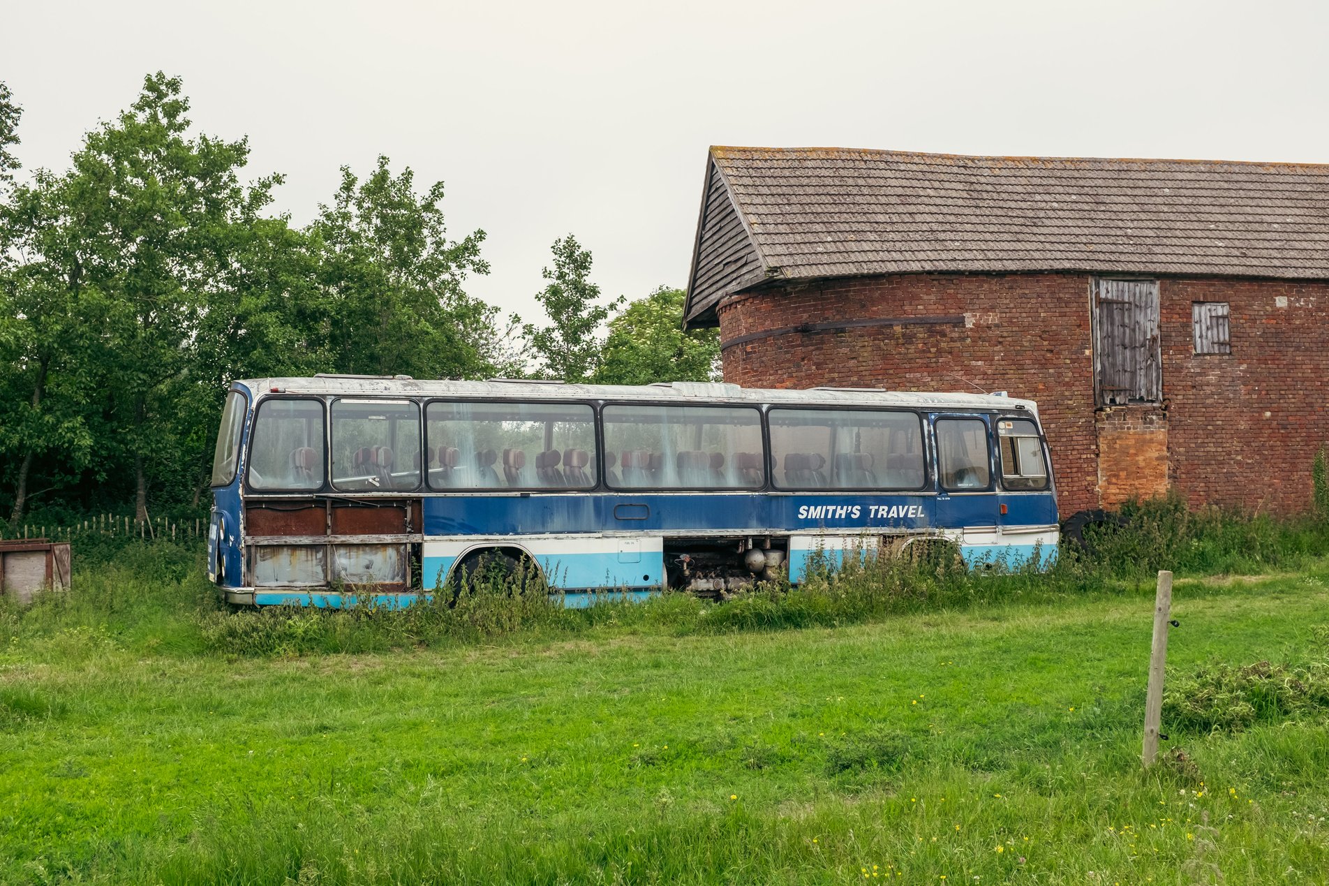 abandonded blue and white coach next to barn