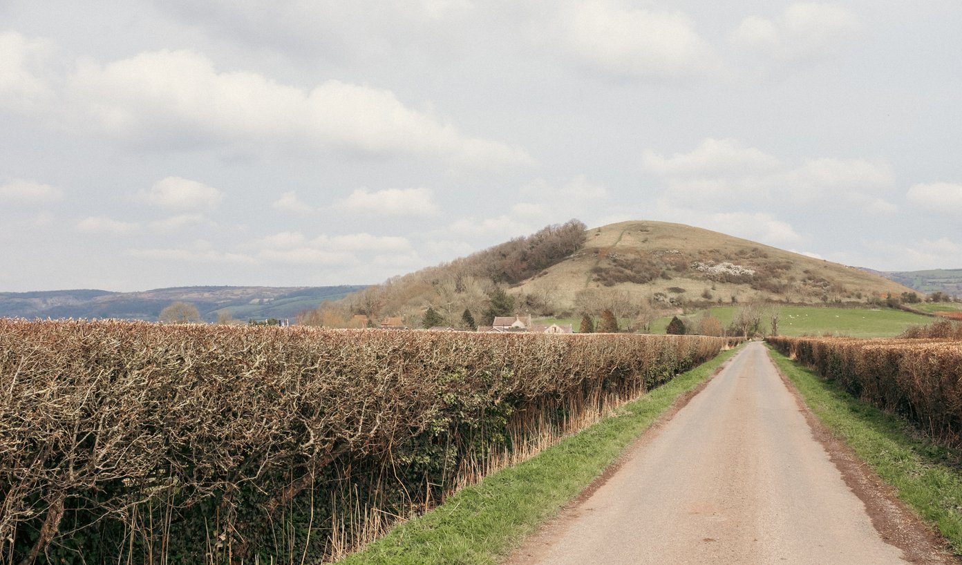 straight country lane with hill in background