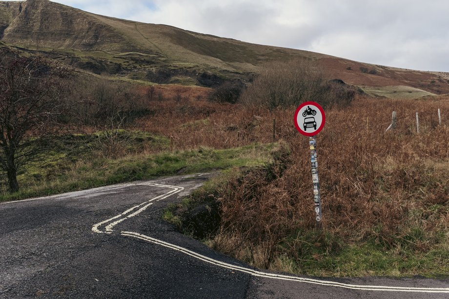mountain road with yellow lines and no vehicles sign post