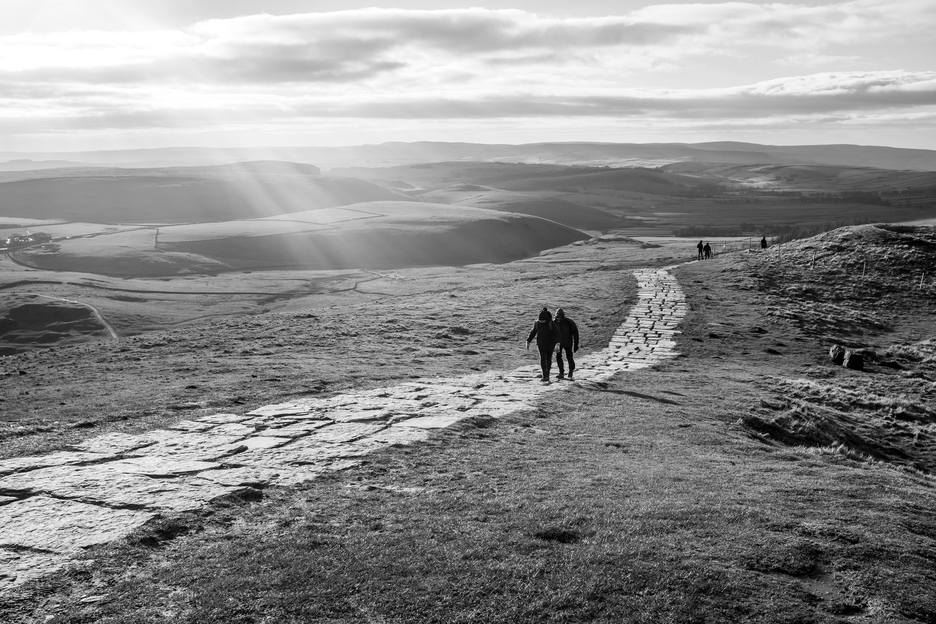 walkers on stone mountain path in winter sunshine