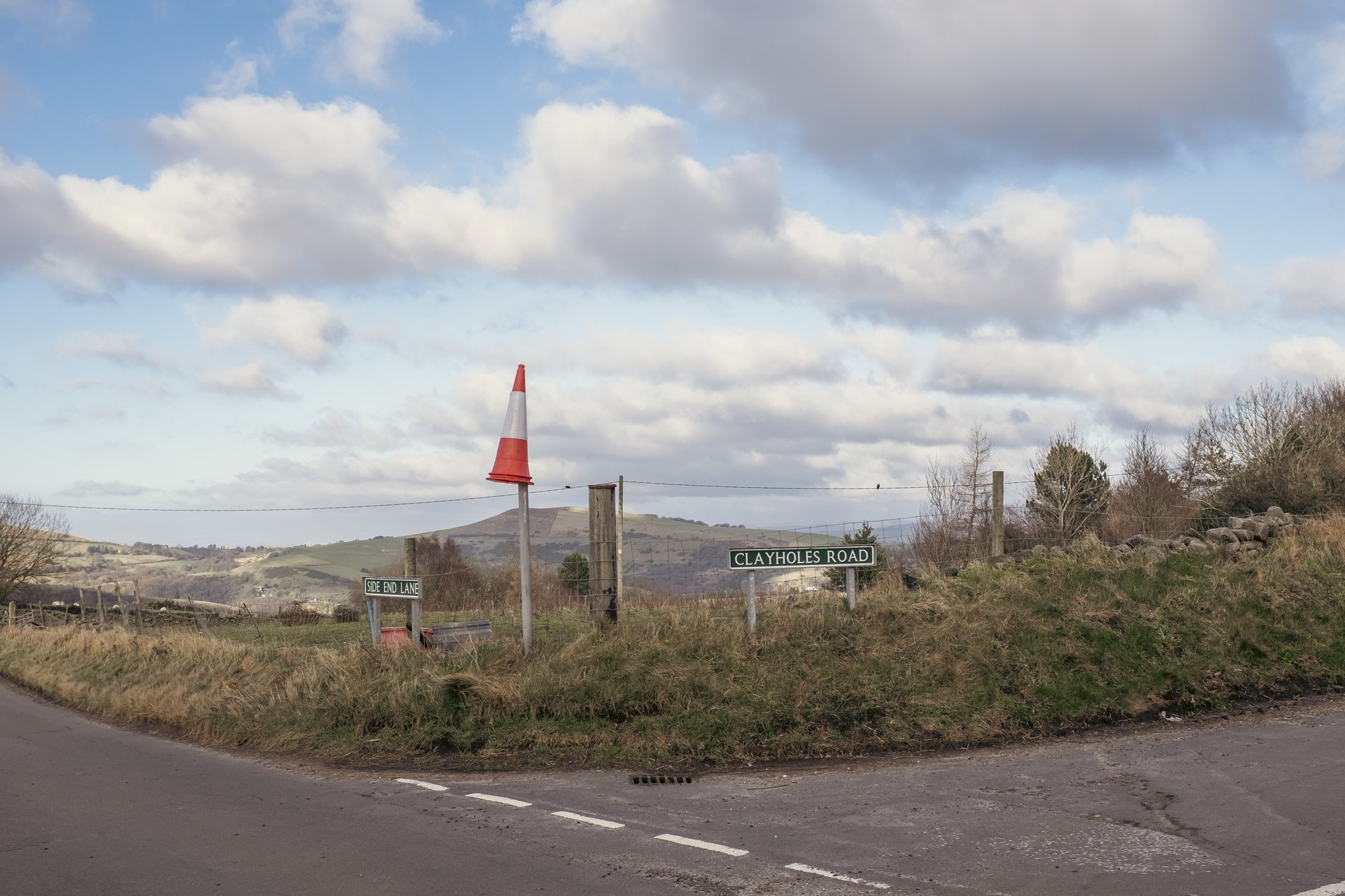 rural road junction with traffic cone balenced on fence post
