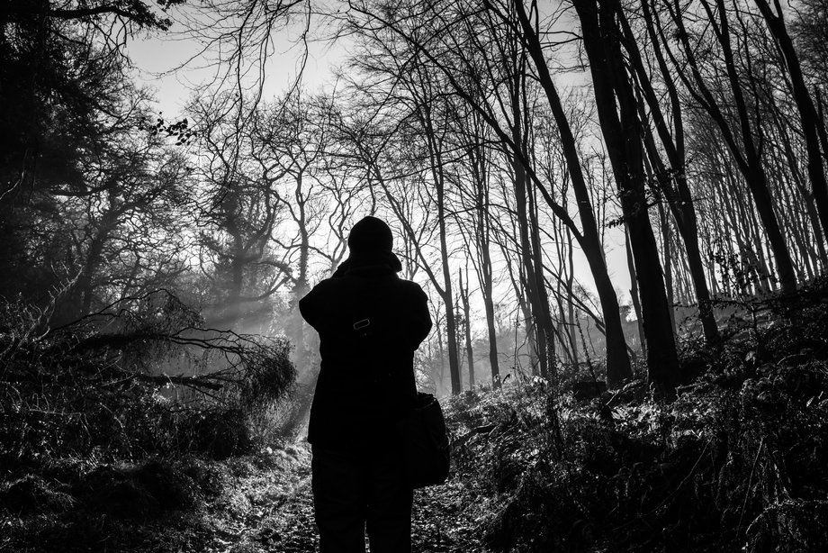 black and white silhouette of person taking photo in woods