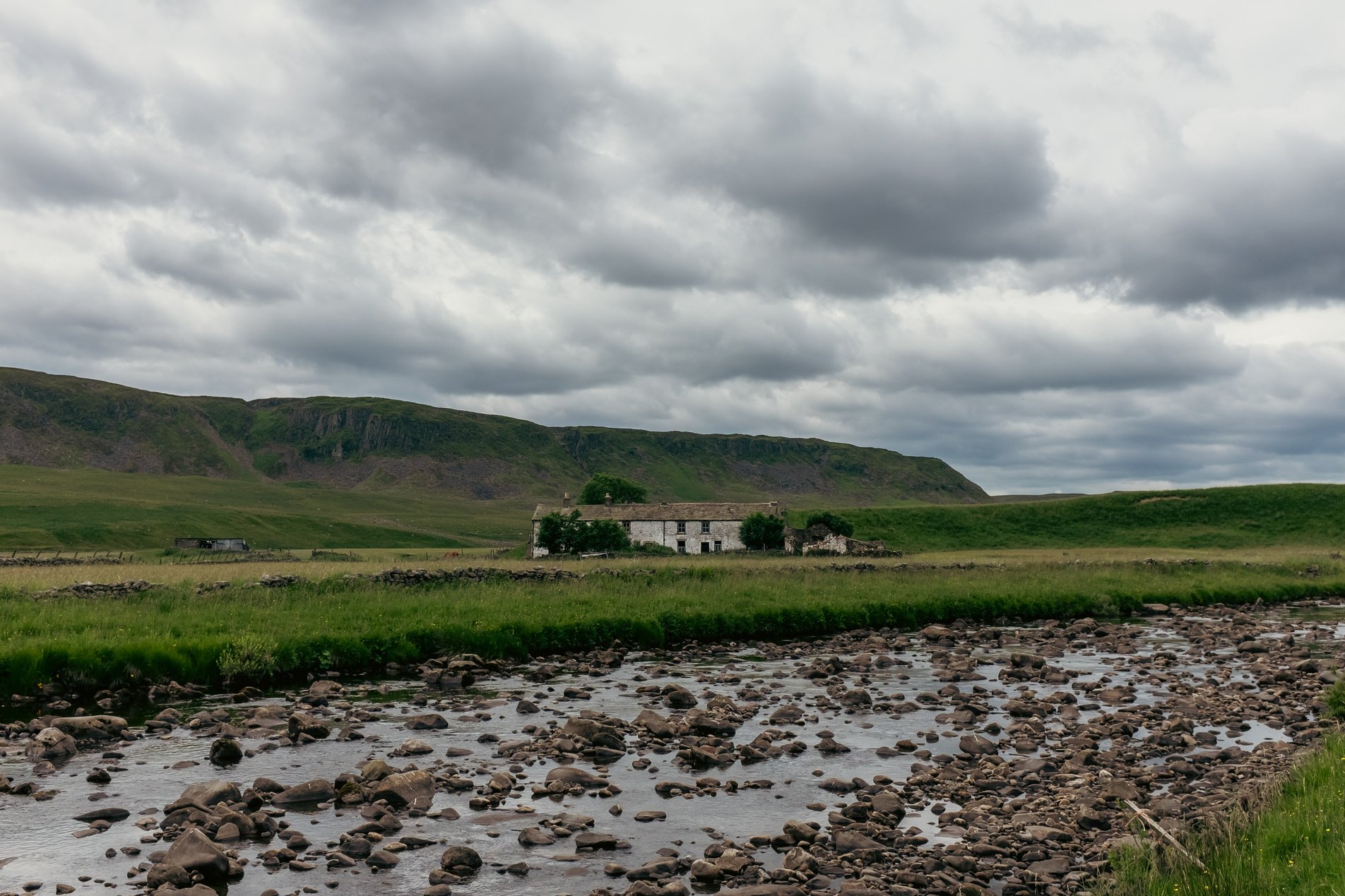 tumbledown house between river and hills